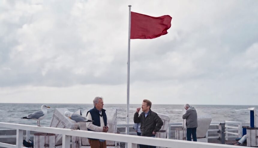 Zwei Möwen sitzen auf dem weißen Geländer der Westerländer Strandpromenade, dahinter Strandkörbe und die Nordsee