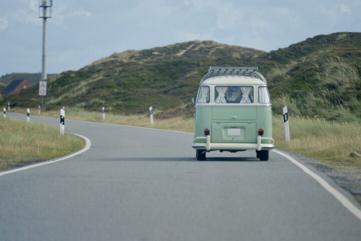 Grüner VW Bulli fährt auf einer Straße durch die Dünen auf Sylt